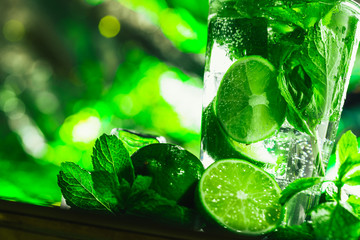 glass of mojito with lime and mint close-up ice cube on a dark background