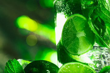 glass of mojito with lime and mint close-up ice cube on a dark background