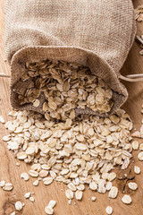 oat flakes cereal in burlap sack on wooden table.