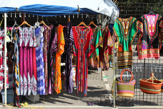 Colorful African Dashikis, Dresses, And Woven Bags At An Outdoor Flea Market