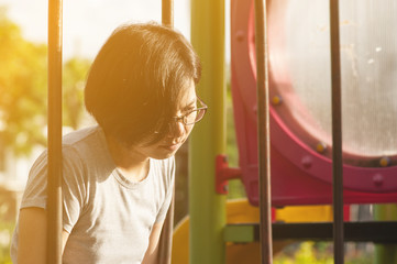 Portrait of Sadness Asian woman sitting on swing at playground background.