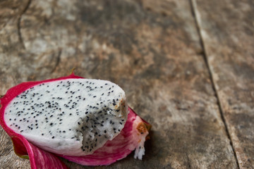 A piece of dragon fruit which was bite. Dragon fruit on the wooden board