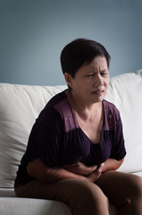 Senior Asian woman having stomach ache.