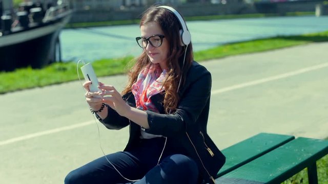 Happy girl listening music on headphones and doing selfies on smartphone
