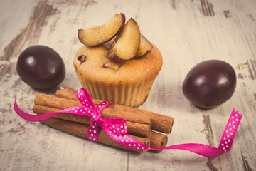 Vintage photo, Fresh baked muffins with plums and cinnamon sticks on old wooden background, delicious dessert