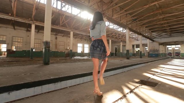 Girl dancing in an abandoned factory in the sun, and the dust raised