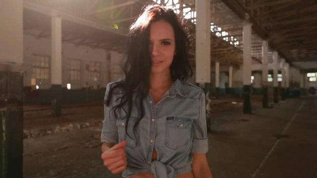 Girl dancing in an abandoned factory in the sun, and the dust raised