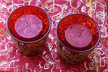 red candles in a round red glass candlesticks