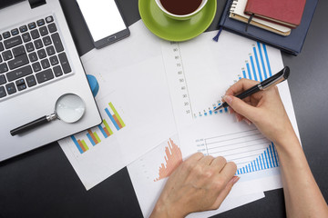 closeup of a young woman checking accounts. Office desk table with supplies top view