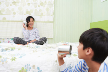 Obraz na płótnie Canvas Mixed-race children enjoying playing together with tin phone