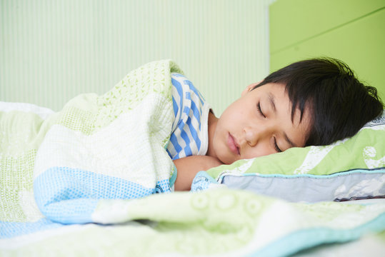 Preteen mixed-race boy sleeping in his bed