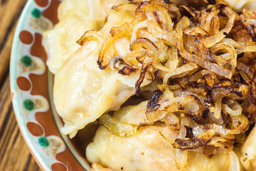 Dumplings with meat and onions. Selective focus. Close up fresh boiled dumplings with hot steams on wood plate. Chinese food on rustic old vintage wooden background. 