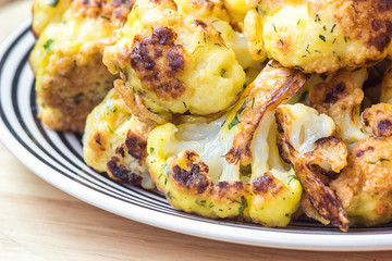 roasted cauliflower in white plate on wooden background