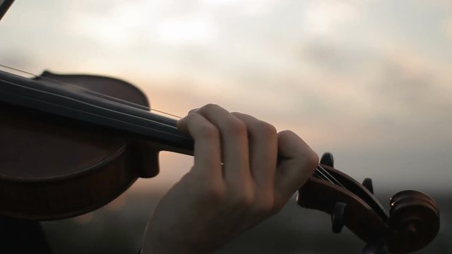 Violin. Violinist playing at sunset. Strings violin and bow. Young violinist playing at sunset. Close-up of strings and bow. Music, art. Musician playing violin, classic music
