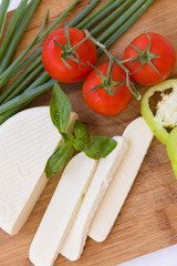 Homemade soft cheese Suluguni with tomatoes, paprica, onions and fresh basil on a wooden board. Healthy food concept