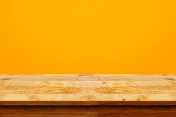 Empty top of wooden table on yellow background.