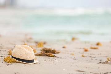 Obraz premium Nice straw hat laying on the sand. Beautiful ocean beach background. Outdoors. Vacation time. End of summer vacations. Dreaming of holidays by the sea. Traveling.