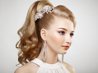 Fashion portrait of young beautiful woman with jewelry and elegant hairstyle. Blonde girl with long wavy hair. Perfect make-up.  Beauty style woman with diamond accessories