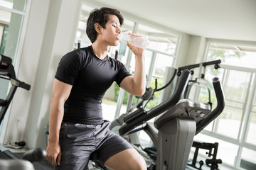 Fototapeta na wymiar Asian men are drinking clean water While cycling exercise at the