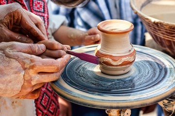 Hands working on pottery wheel. Sculptor, Potter. Human Hands creating a new ceramic pot. Female Potter creating a bowl on a Potters wheel the master potter helping her. Pottery Skill Workshop Concept