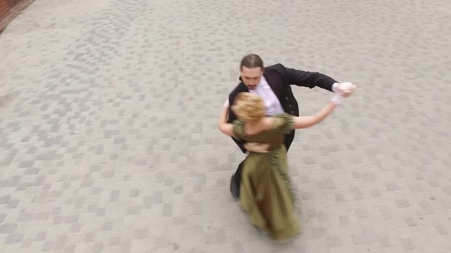 Couple of young man and woman dancing in historical costumes in the street. Top view. 4K