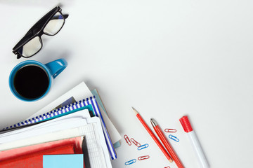 Office table desk with supplies, blank note pad, cup, pen, pc, crumpled paper, flower on white background. Top view