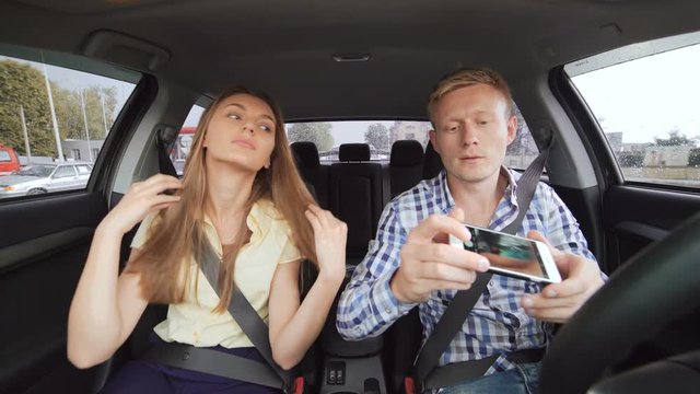 Young funny couple making selfie in a car. 4K