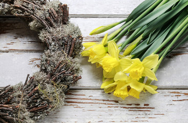 Easter wreath and bouquet of yellow daffodils on wood