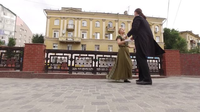 Couple of young man and woman dancing in historical costumes in the street. 4K