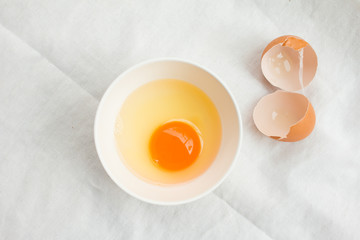 Broken eggs in white bowl