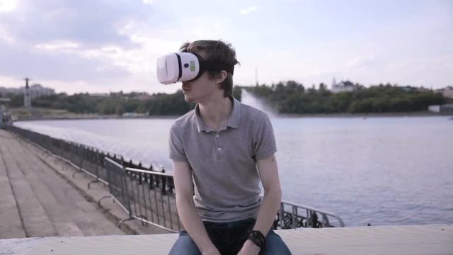 Young handsome man wearing virtual reality goggles in a city. HD.
