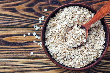 Food. Oatmeal on the table. Dry rolled oat flakes oatmeal in brown bowl on old wooden table.