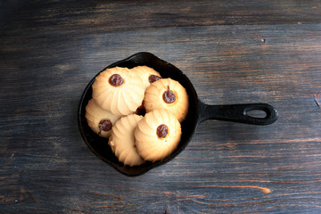 Cookies in cast iron pan, wooden table,top view. Special light.