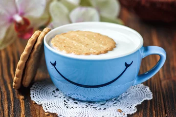 Fotobehang Good morning or Have a nice day message concept - bright blue cup of milk with cookies. Cup of milk with smile. Health and diet concept on the wooden table, close up. © bozhena_melnyk