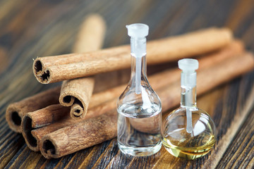 Essential oil in glass bottle with cinnamon sticks on wooden background. Beauty treatment. Spa concept. Selective focus.