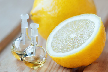 Essential aroma oil in glass bottle with fresh, juicy lemon fruit on wooden background. Beauty...