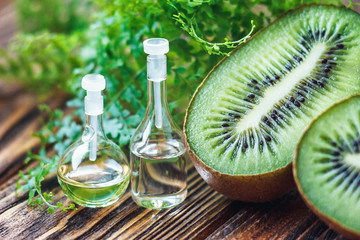 Essential oil in glass bottle with fresh, juicy kiwi fruit and green leaves-beauty treatment. Spa concept. Selective focus.