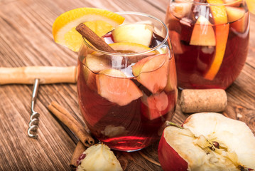 Homemade  red wine sangria with apples and oranges on a wooden table.