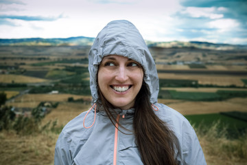 Young woman smiling after a long hike in windy weather, looking away from camera
