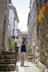 Fototapeta na wymiar Tourist walking dow an old italian alley in Vico del Gargano, Apulia, Italy