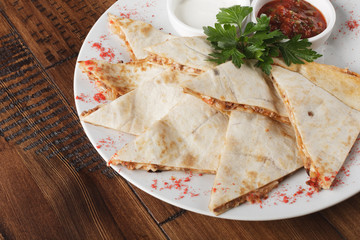 quesadilla with beef and chicken on brown wood table. quesadilla and sauce.