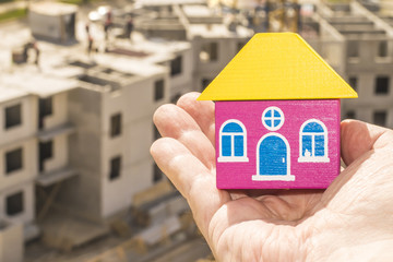 Wood house in hand on a background of construction