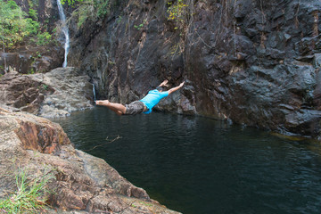 Man jumping on Waterfall in deep rain forest jungle Thailand
