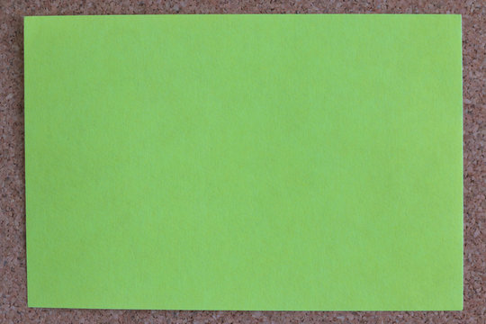 green reminder sticky note on cork board, empty space for text