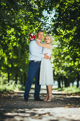 Fototapeta premium Bride and groom at wedding day, walking outdoor at summer on nature. Bridal couple, happy newlywed woman and man embracing. Loving wedding couple outdoor. 