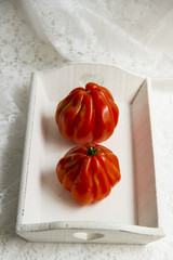 Buffalo heart tomatoes, on white wooden tray. White background, close up. 