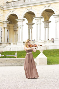 Beautiful smiling girl playing on the violin outdoors. Musician for the wedding.Violin under the open sky

