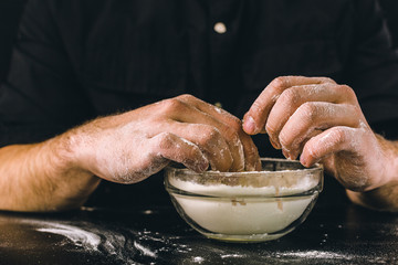 the chef hands are dropping flour over a wooden table