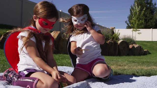 Young girls dressed as superheroes having picnic outside - 4K