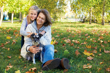 Naklejka na ściany i meble Portrait of smiling woman with cute little girl in autumn park